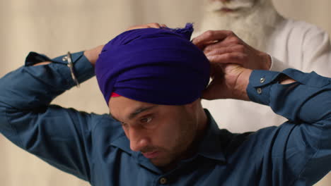 Fotografía-De-Estudio-De-Dos-Hombres-Sikh-Atando-Tela-Para-Un-Turbante-Contra-Un-Fondo-Liso.-1