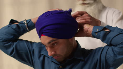 fotografía de estudio de dos hombres sikh atando tela para el turbante contra un fondo plano 1