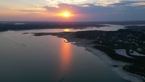 Ein-Boot-Rast-über-Den-Lake-Travis,-Während-Sich-Ein-Feuriger-Sonnenuntergang-Auf-Dem-Wasser-Spiegelt