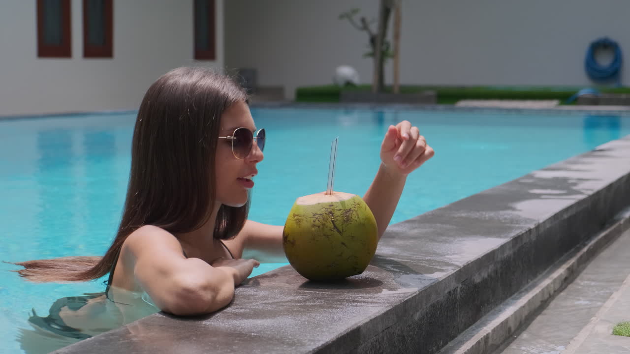 Woman enjoying a coconut drink by the pool
