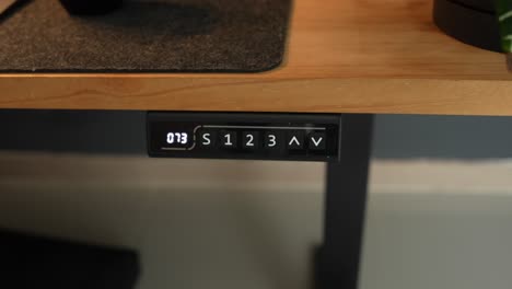 hand pushing button of adjustable standing desk to change height