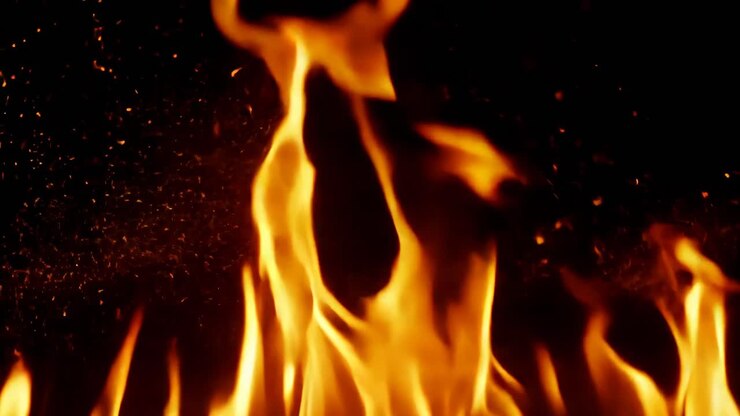 A close up of a fire with its flames reaching up to the sky. The fire is orange and yellow, and it is very hot. The flames are dancing and flickering, creating a sense of movement and energy