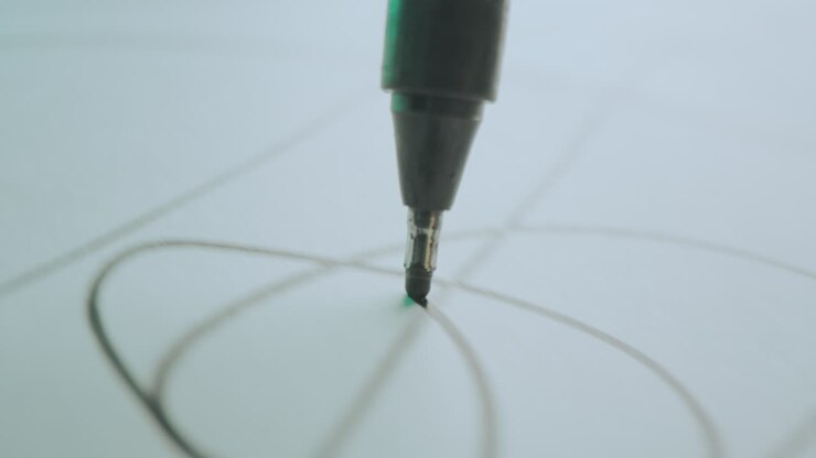 Close-up of a pen drawing lines on paper