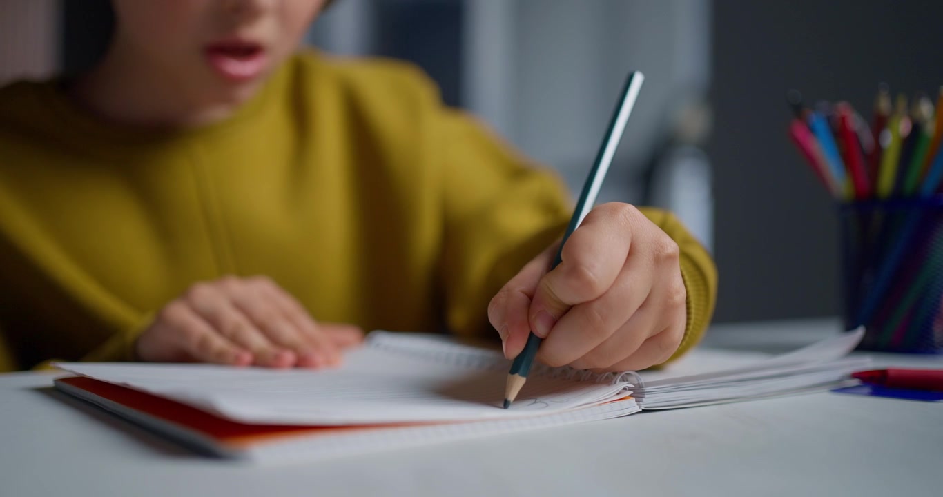 Primo piano della mano di un bambino che scrive su un quaderno