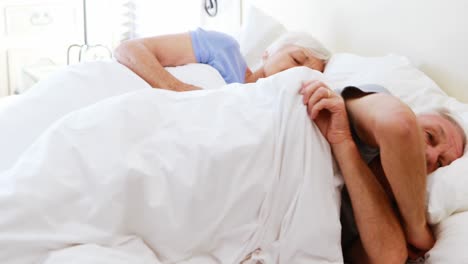 Senior-couple-sleeping-on-bed-in-bedroom