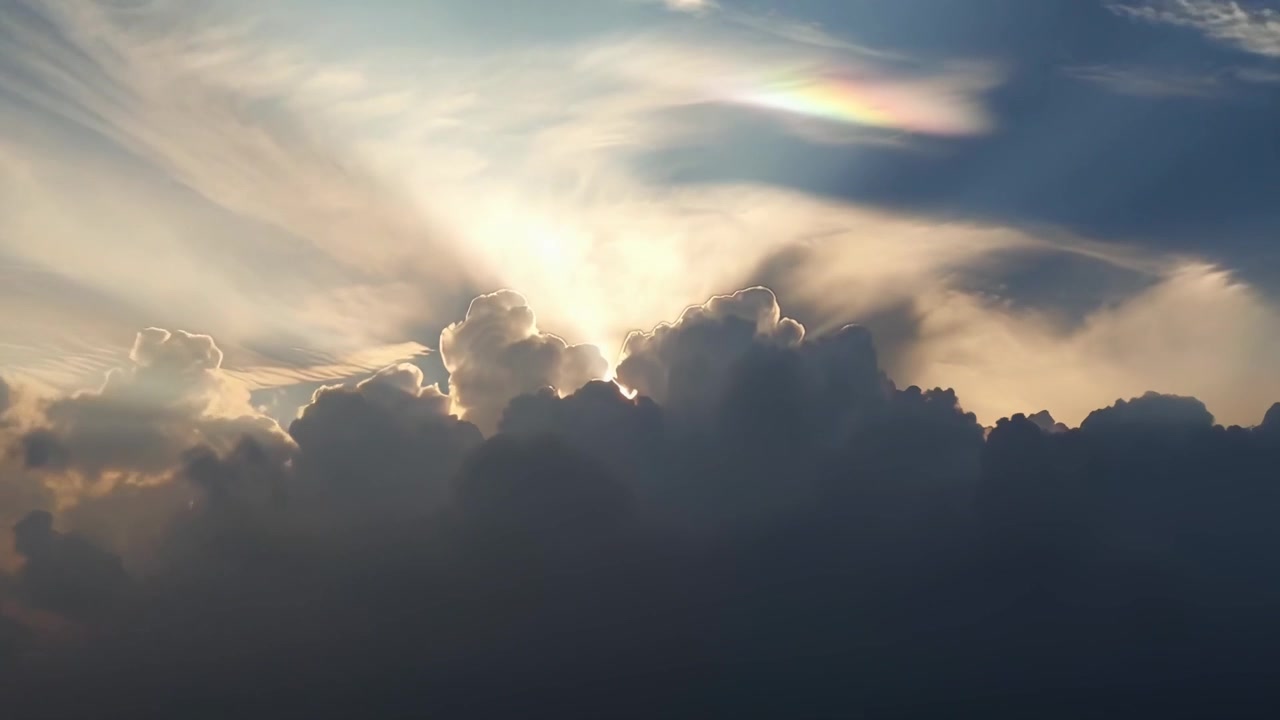 Luce solare che filtra attraverso nuvole scure con una formazione nuvolosa iridescente