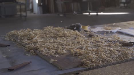 the carpenter cleans the dust and chips from the wood.