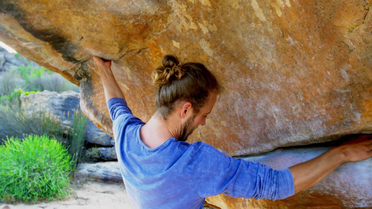 Male hiker climbing rocky mountain in countryside 4k