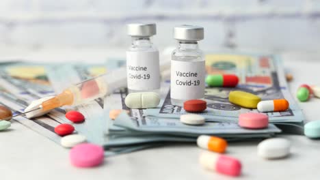 vacuna contra la covid-19 y medicamentos relacionados en billetes de dólares estadounidenses