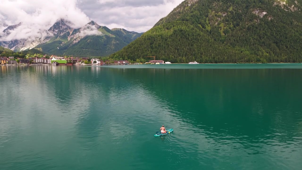 Donna che pratica stand up paddle sul lago Achensee con vista sulle montagne in Austria - ripresa aerea
