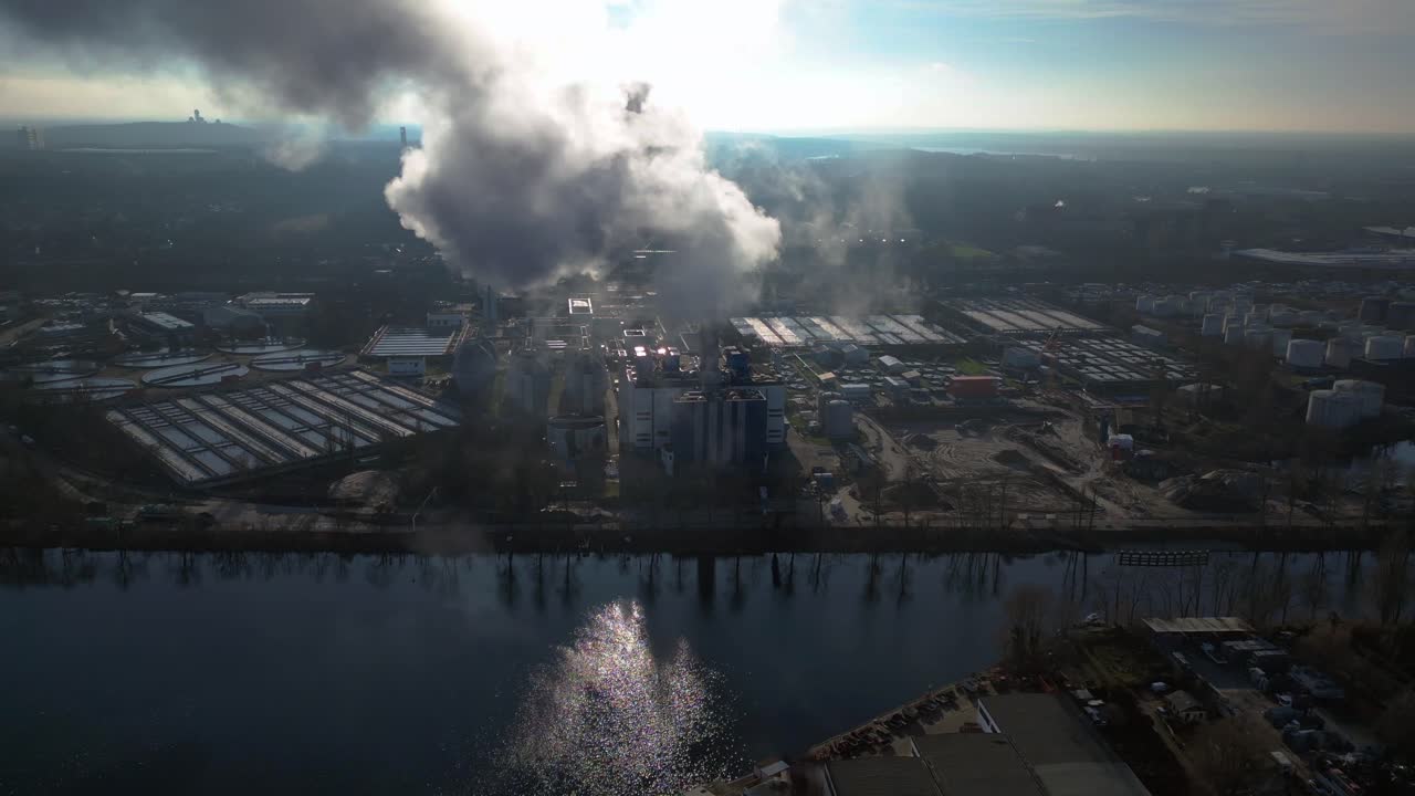 Industrial chimneys emitting white smoke over city skyline under blue sky, concept of pollution. Great aerial view flight wide orbit overview drone