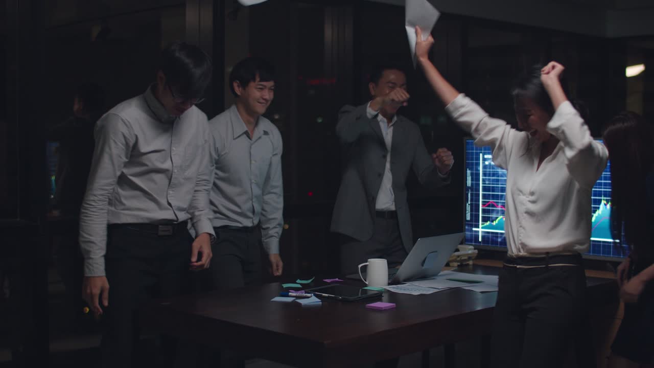 아시아의 사업가들은 성과에 대해 행복한 기분으로 문서를 던지고, 도시의 야간 사무실에서 회의실에서 성공한 결과를 느니다.