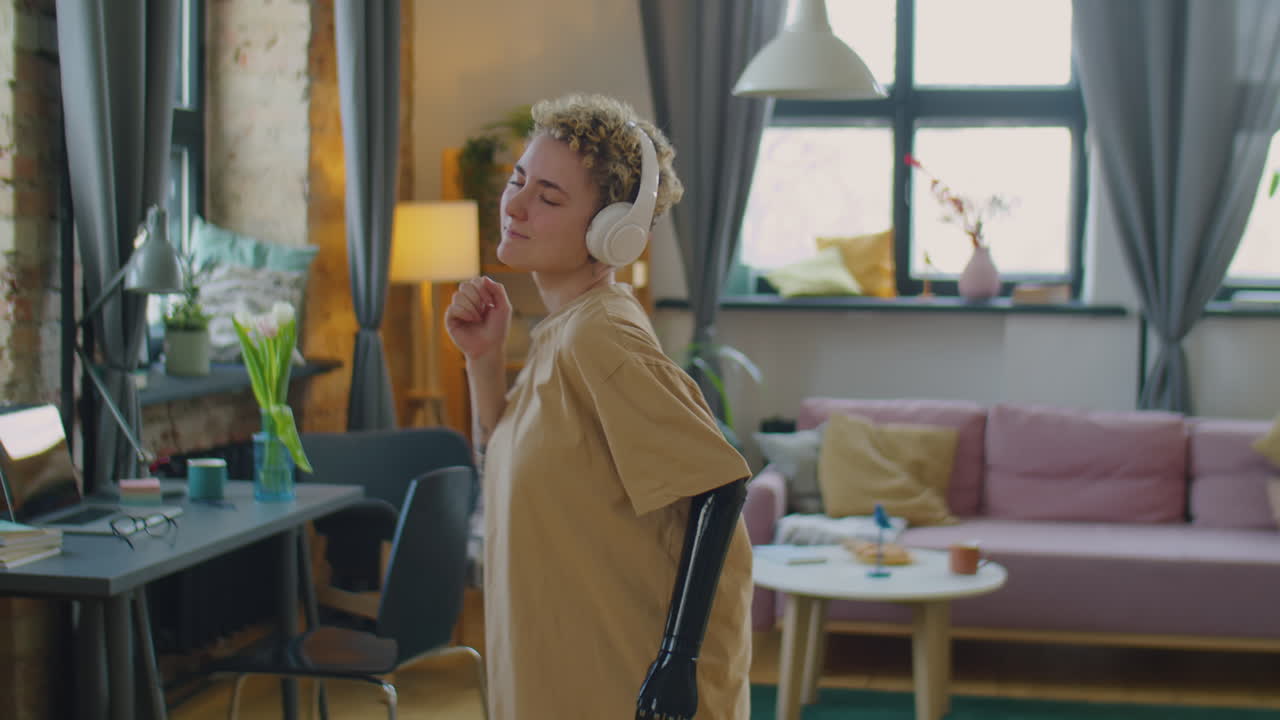 의수 팔을 가진 소녀가 집에서 춤을 춘다