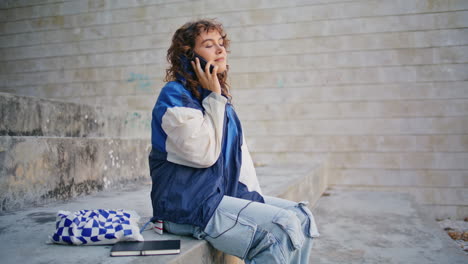 chica informal llamando al teléfono en la calle. mujer rizada comienza una conversación telefónica