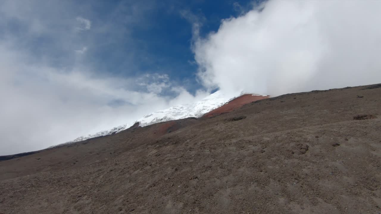 Establishing overview of Cotopaxi volcano, Ecuador, framed by a deep blue sky and rugged volcanic slopes