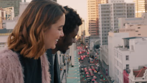 happy multiracial couple laughing having fun enjoying rooftop view of city chatting sharing connection friends drinking alcohol hanging out on weekend