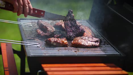 Man-flipping-barbecued-ribs-on-coal-grill-in-his-garden