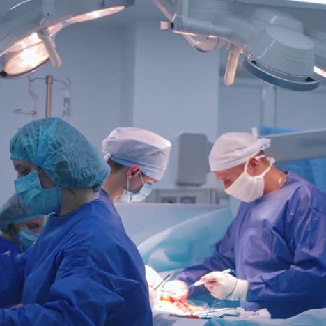 teamwork of surgeons in modern clinic. professional doctors in medical uniform operate the patient. female assistant giving sterile instruments during the operation.