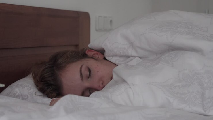 Vista lateral de chica durmiendo en la cama, luz de la mañana, primer plano de cara o cabeza