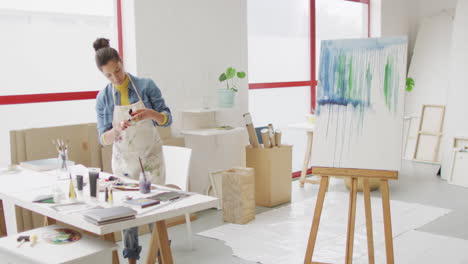 video of biracial female artist preparing paints and working in studio