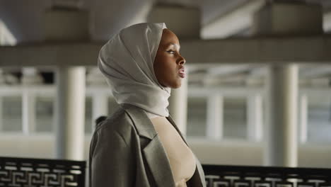 young black muslimah walks looking around along waterfront