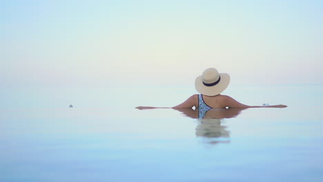 A-woman-with-her-back-to-the-camera-appears-to-be-floating-in-the-middle-of-a-body-of-water