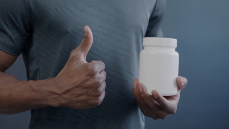 man holding a supplement bottle with thumbs up