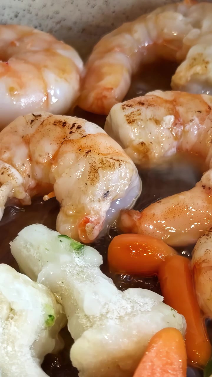 Saftige rejer og grøntsager steger på en pande, hvilket skaber en sydende og appetitlig scene.