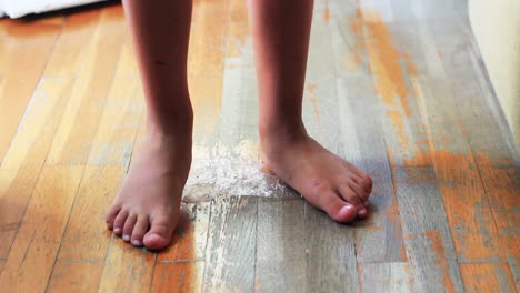 legs of a child, barefoot, stepping on a plastic bottle before throwing