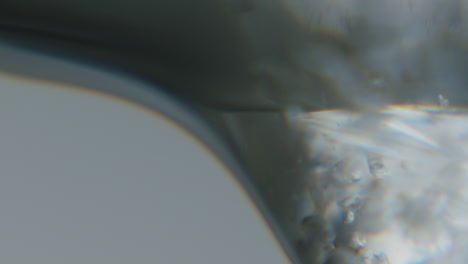 Weiße-Transparente-Flüssigkeit-Mit-Kleinen-Kristallen-Im-Inneren,-Die-Sich-Langsam-Bewegt