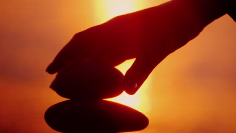 a hand lays a stone on top of a tower of stones harmony and balance concept