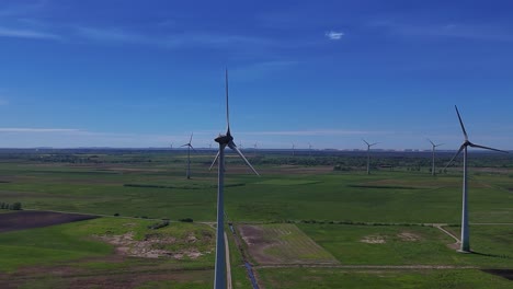 wind turbines spinning on a sunny day in a vast green field, aerial view