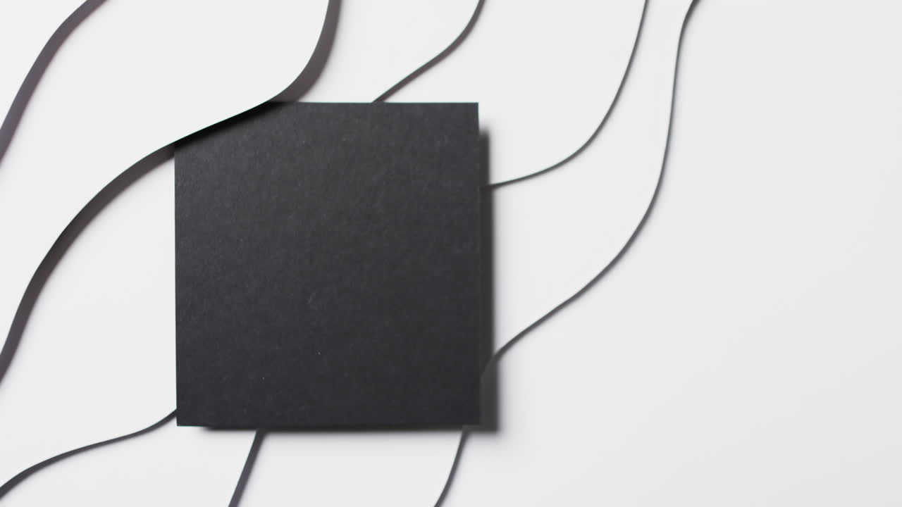 Video of close up of square of black paper on waves cut out and copy space on white background