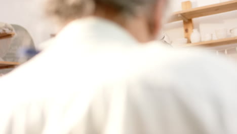 happy african american female potter and others, working and smiling in pottery studio, slow motion