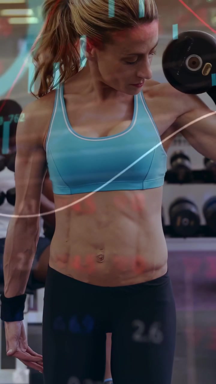 Donna che solleva un manubrio in palestra, avviando grafici finanziari animati e monitorando i bicipiti.