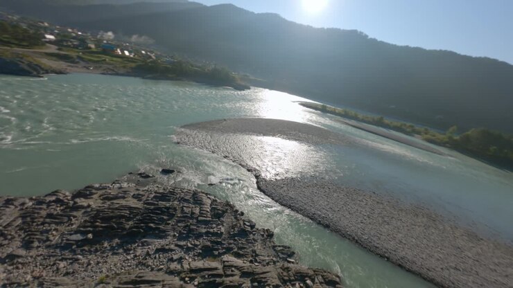 Vista aerea dinamica di un rapido flusso d'acqua di un fiume di montagna, scogliera rocciosa, isola e ponte pedonale