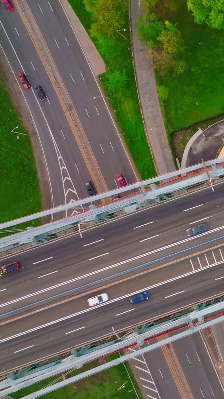 Cars and lorries passing by the lively motorways. Top view on the road junctions in busy metropolis. Vertical video