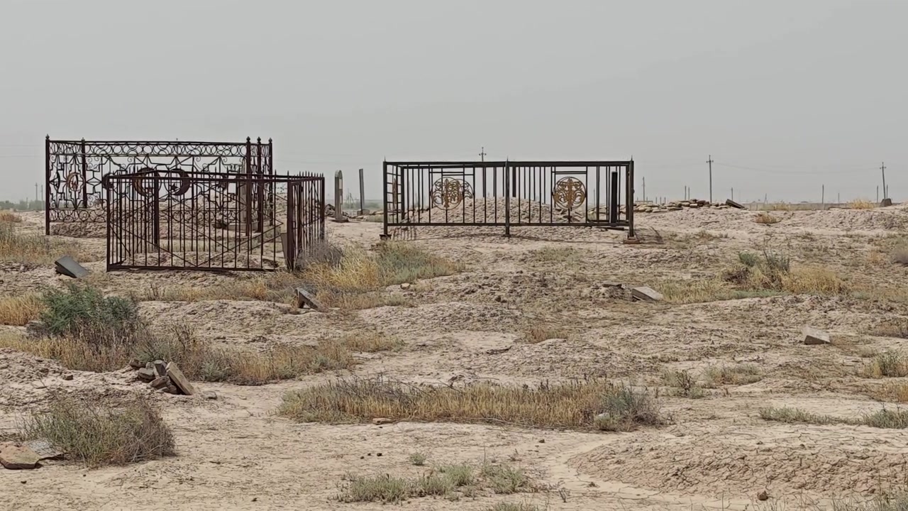 Vecchio cimitero con recinzioni metalliche in un paesaggio arido