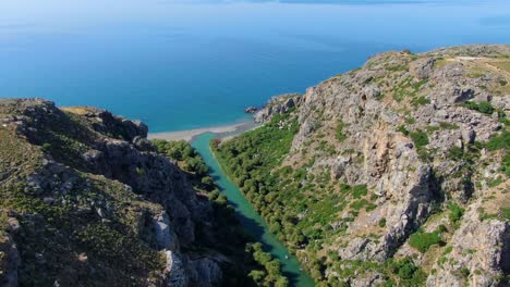 wide overhead drone shot of a natural freshwater spring feeding into the aegean sea on the island of crete