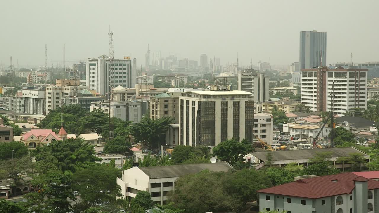 Victoria Islandin, Lagos, Nigeria, sumuinen horisonttikuva, jossa keski- ja korkeat toimistorakennukset kohoavat vihreiden asuinkerrostalojen yläpuolelle, kuvaten kaupungin finanssialuetta