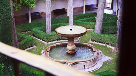 fixed shot from balcony of old fountain in green garden, al hambra de granada, spain