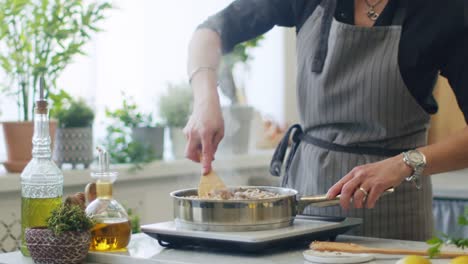 person stirring hot veal shanks in frying pan