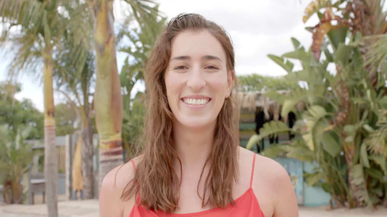 retrato de una feliz mujer caucásica mirando a la cámara sobre las palmeras.