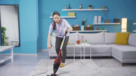 una joven asiática limpiando la casa con una aspiradora.