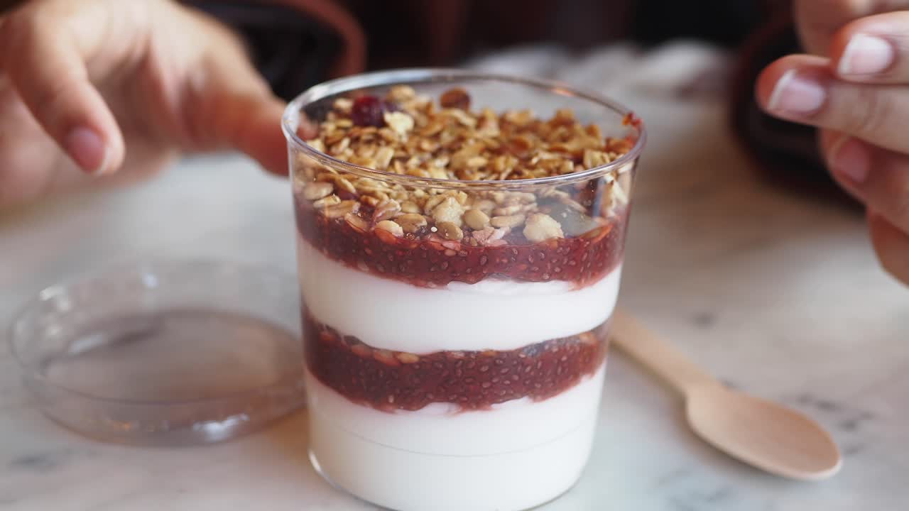 Gros plan sur quelqu'un mangeant un parfait au granola