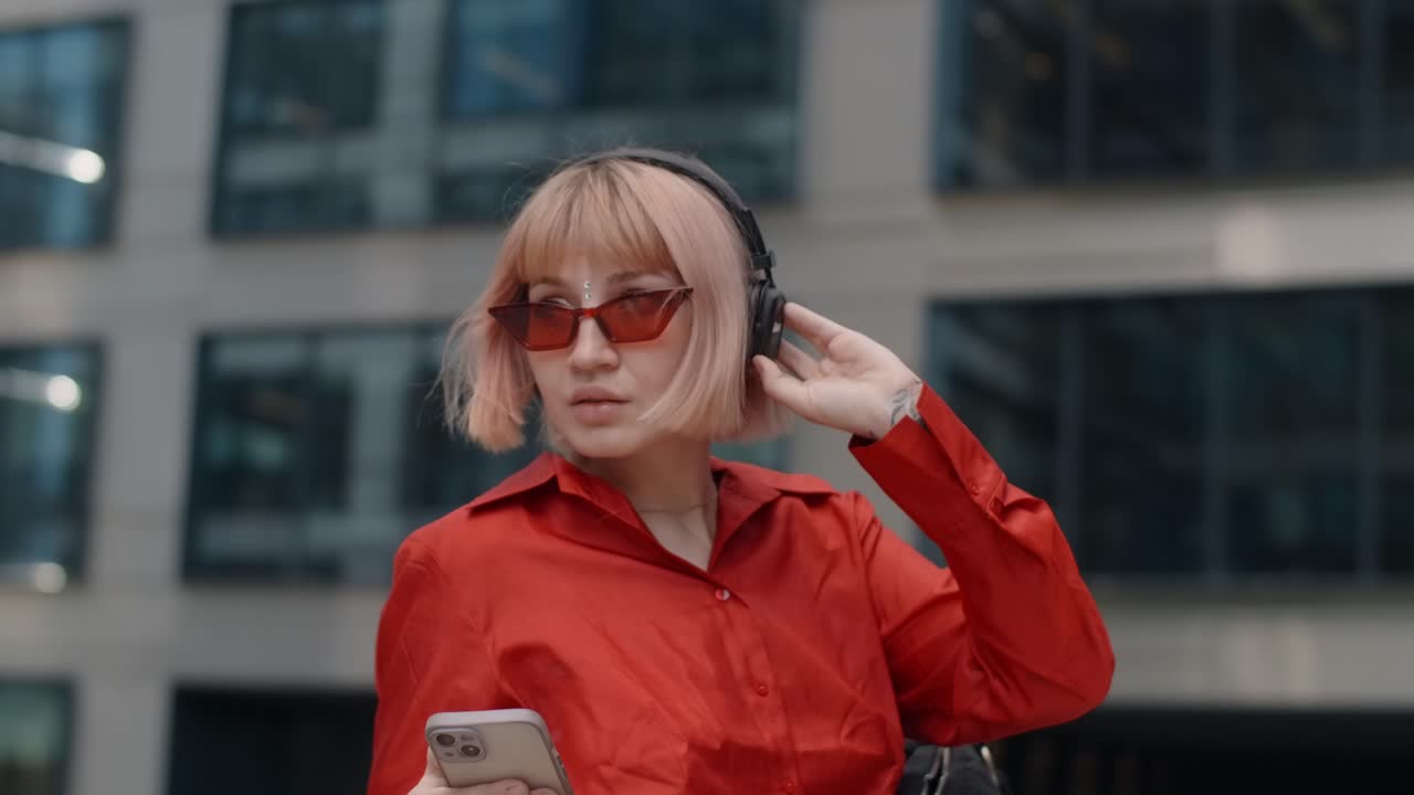 Stylish Woman Listening to Music and Checking Phone in City