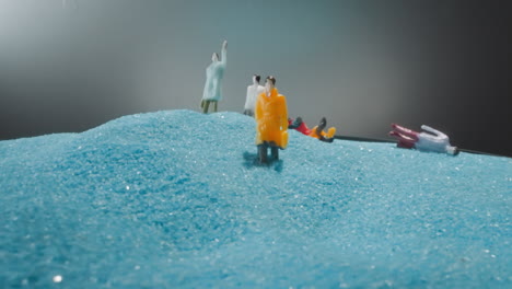 figures of people standing on big sandy hill under grey sky