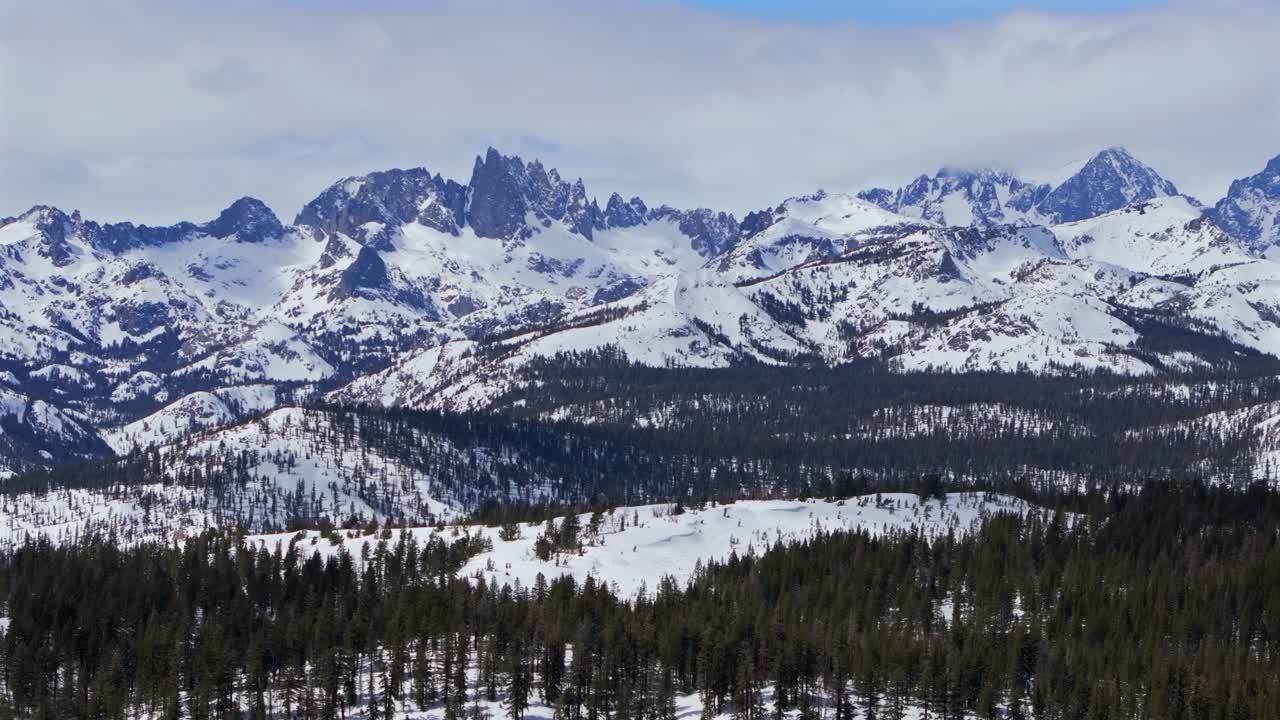 The Hemlocks Mammoth Mountain ski snowboard resort winter spring sunny blue sky morning clouds aerial drone California Minarets jagged towering peaks Inyo National Forest parallax right motion