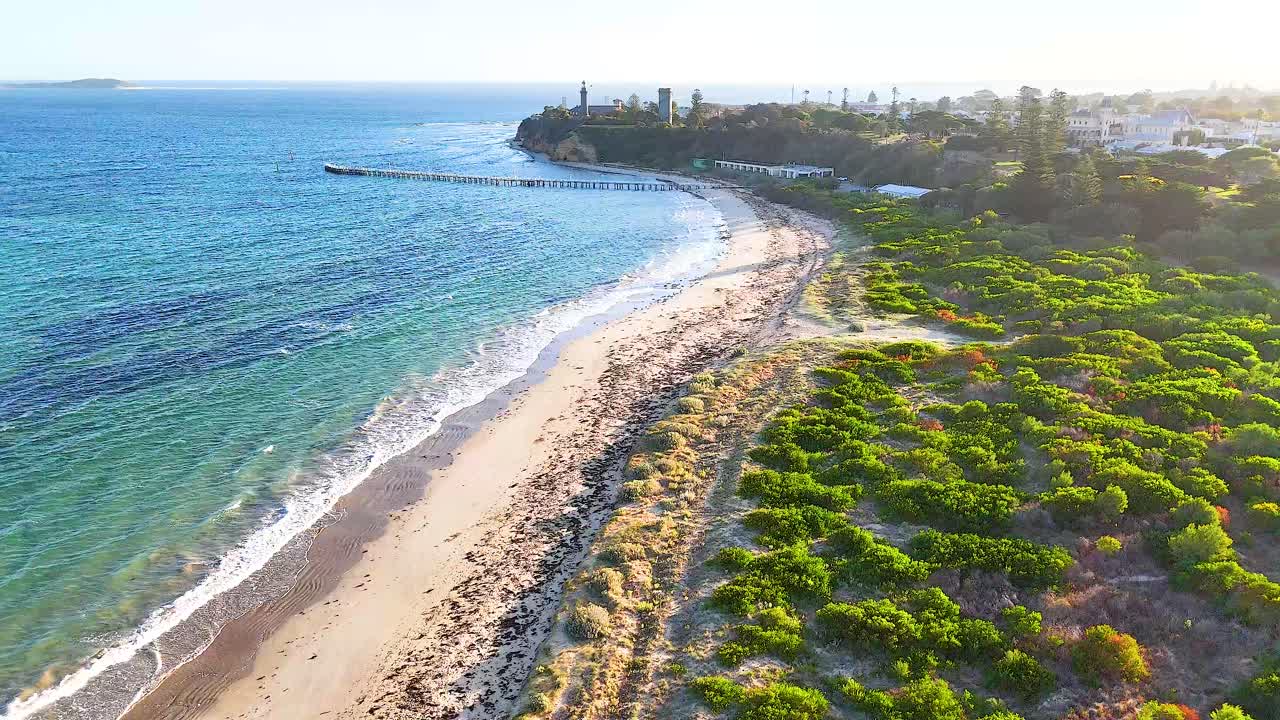 Drone footage captures the serene coastline of Bellarine Peninsula, showcasing vibrant greenery and clear blue waters under bright sunlight