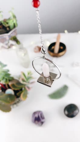 rose quartz crystal pendulum with succulents and stones